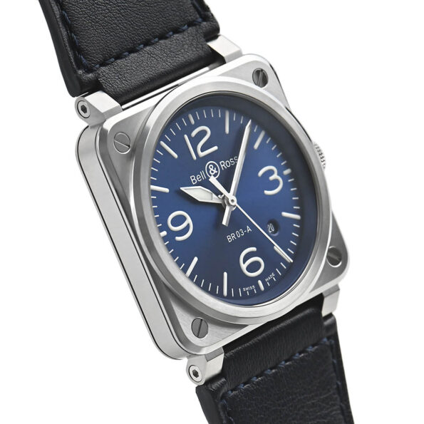Right-side close-up of the Bell & Ross BR 03 Blue Steel watch, highlighting its seamless blue steel case construction, fixed bezel, and the contrast stitching on the attached blue leather strap.